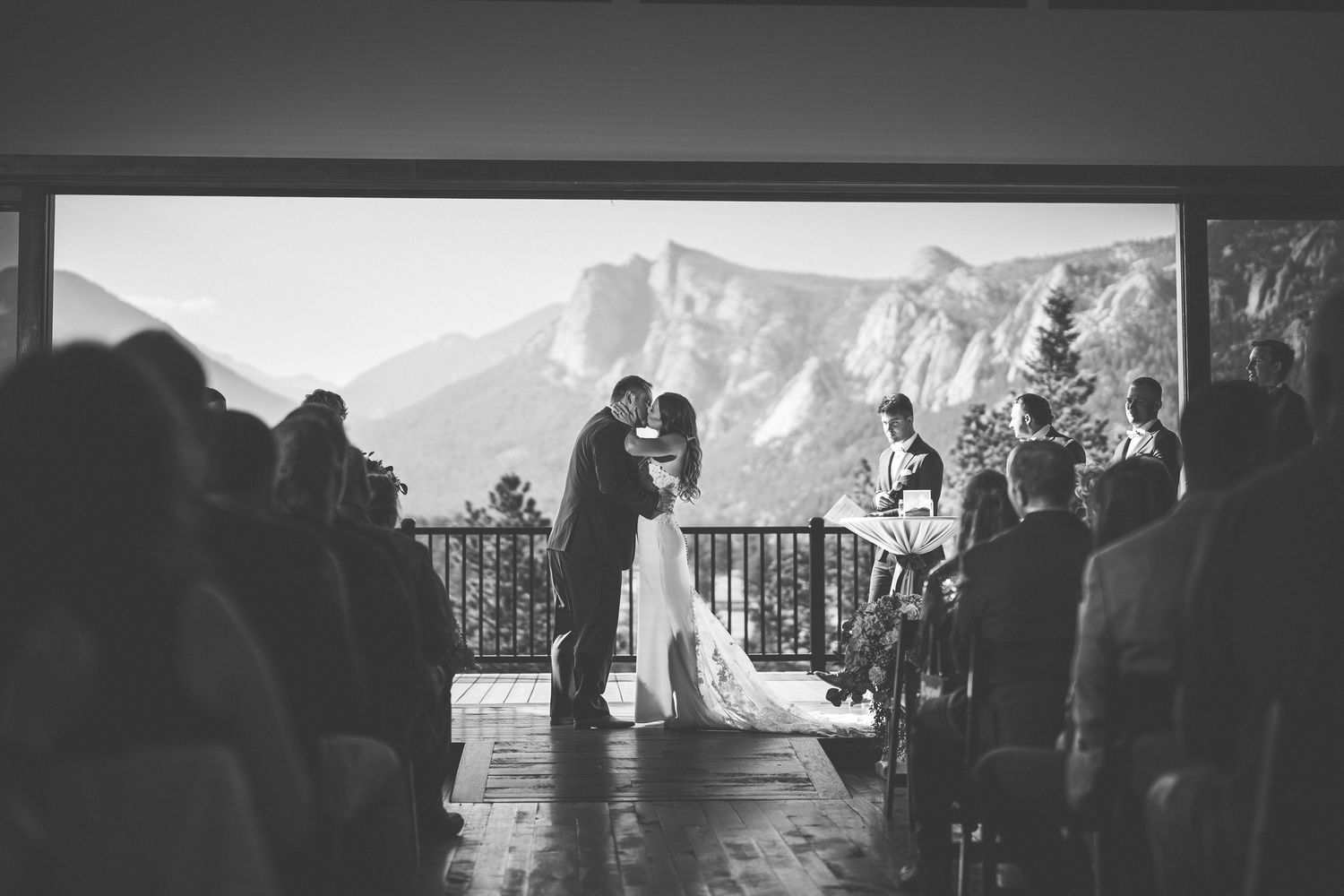 Black and white photo of a couple sharing their first kiss at an outdoor mountain wedding ceremony.