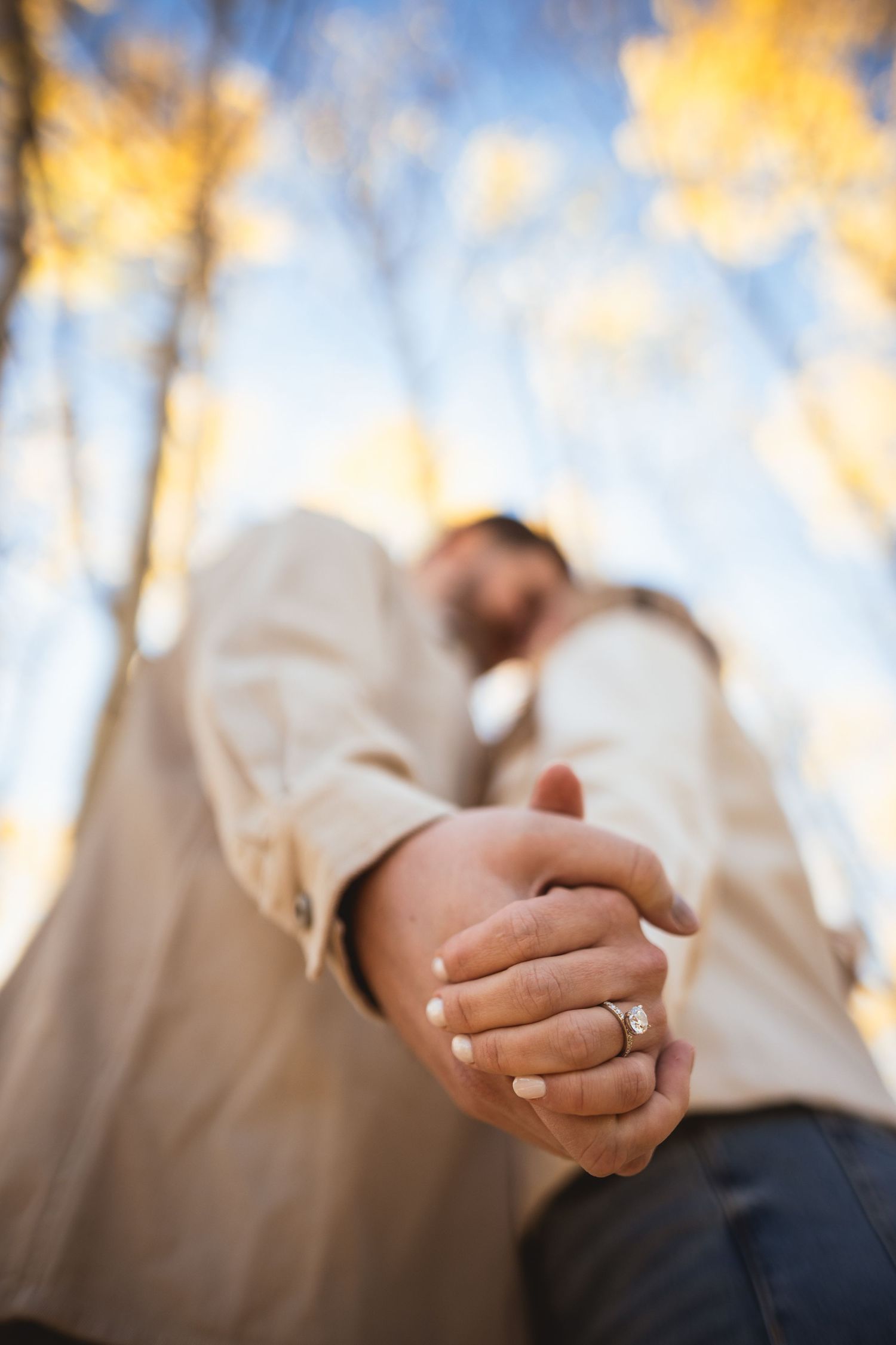 Close-up shot of hands with engagement ring in warm autumn sunlight.