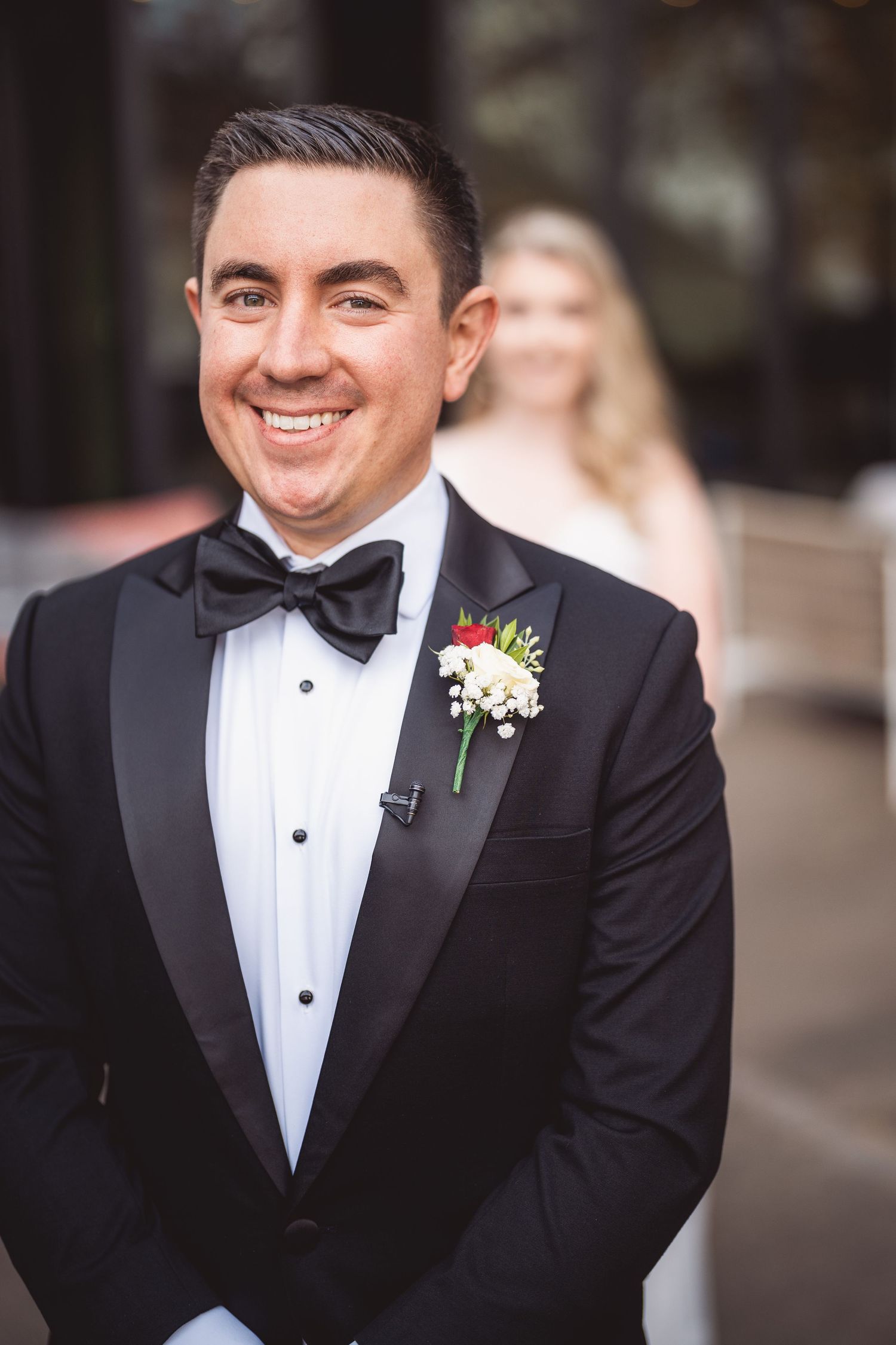 Groom in classic black tuxedo and bow tie smiles for portrait series.