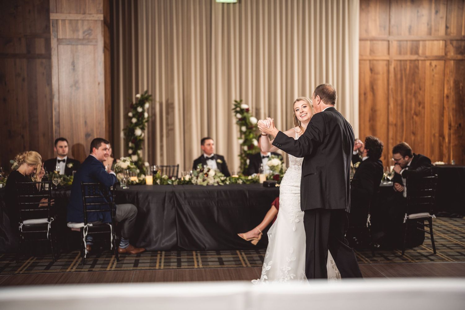 Elegant ballroom wedding reception with draped fabric decor and floral arrangements.