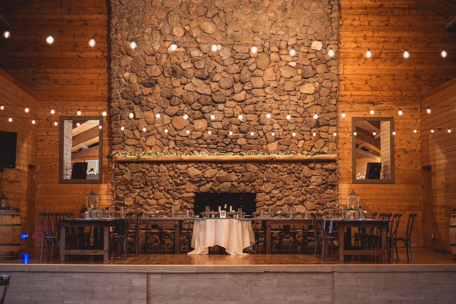 Rustic barn wedding venue with stone walls and twinkling string lights creating romantic atmosphere.
