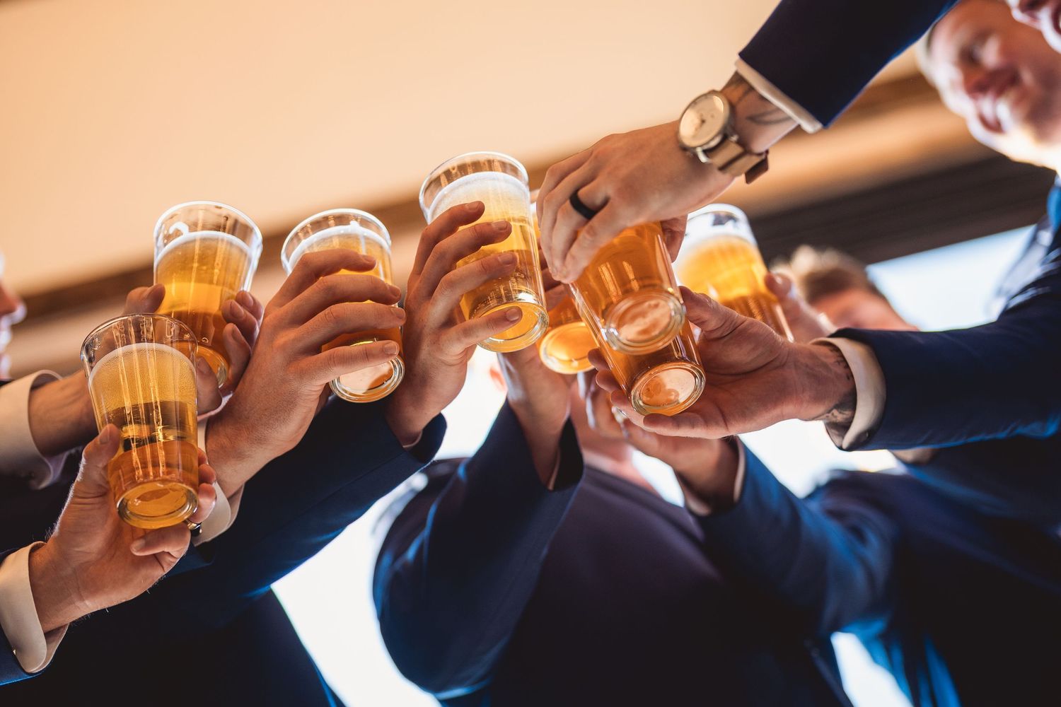 Group of hands toasting with beer glasses in celebration.