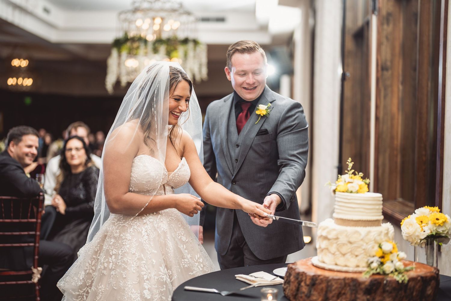 Wedding reception scene with couple and guests enjoying cake cutting festivities.