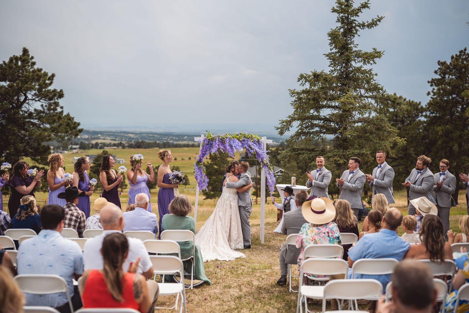 Guests seated at outdoor mountain wedding ceremony with scenic vista.