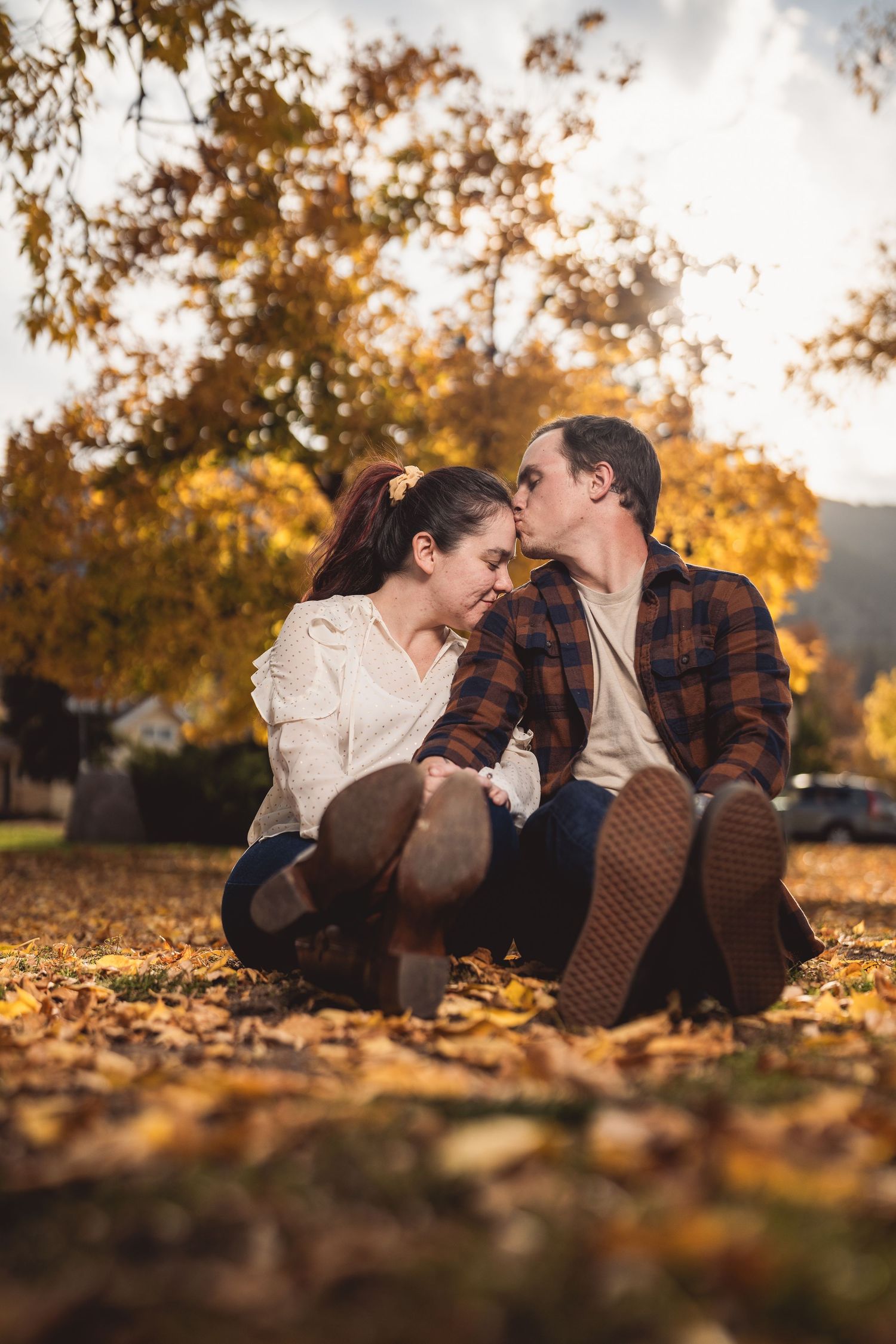 Couple lying in autumn leaves during golden hour photo session.
