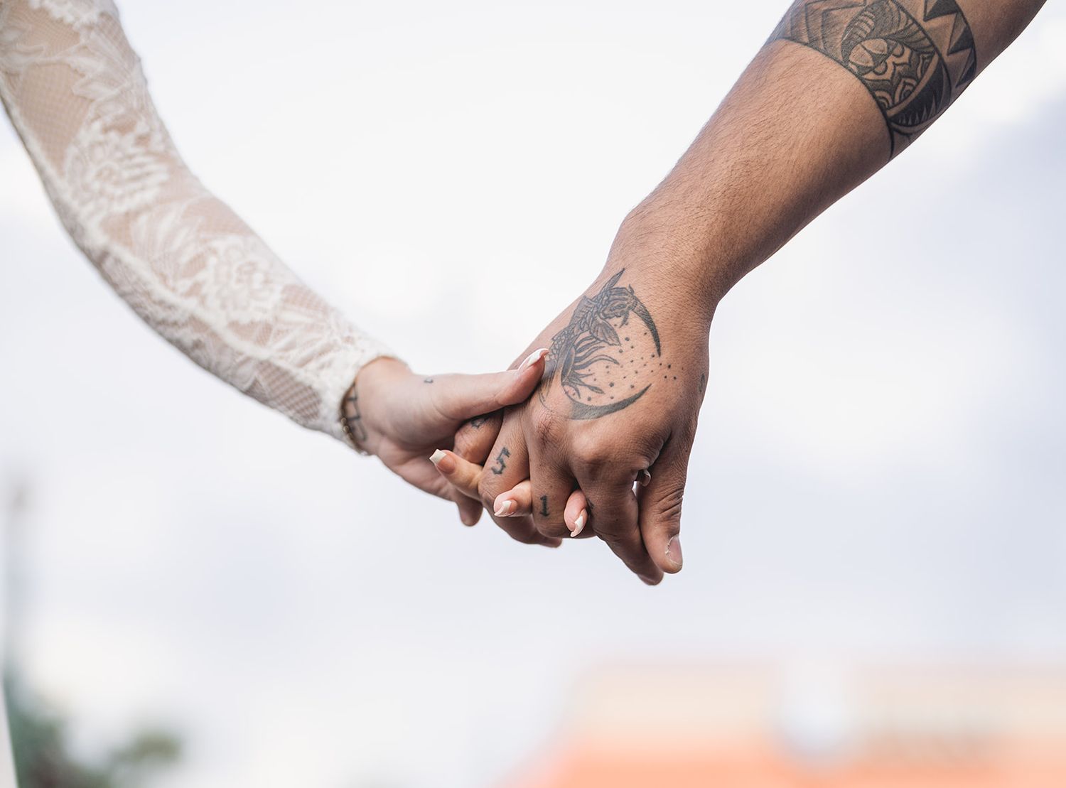 Close-up series of tattooed hands holding each other in natural light.