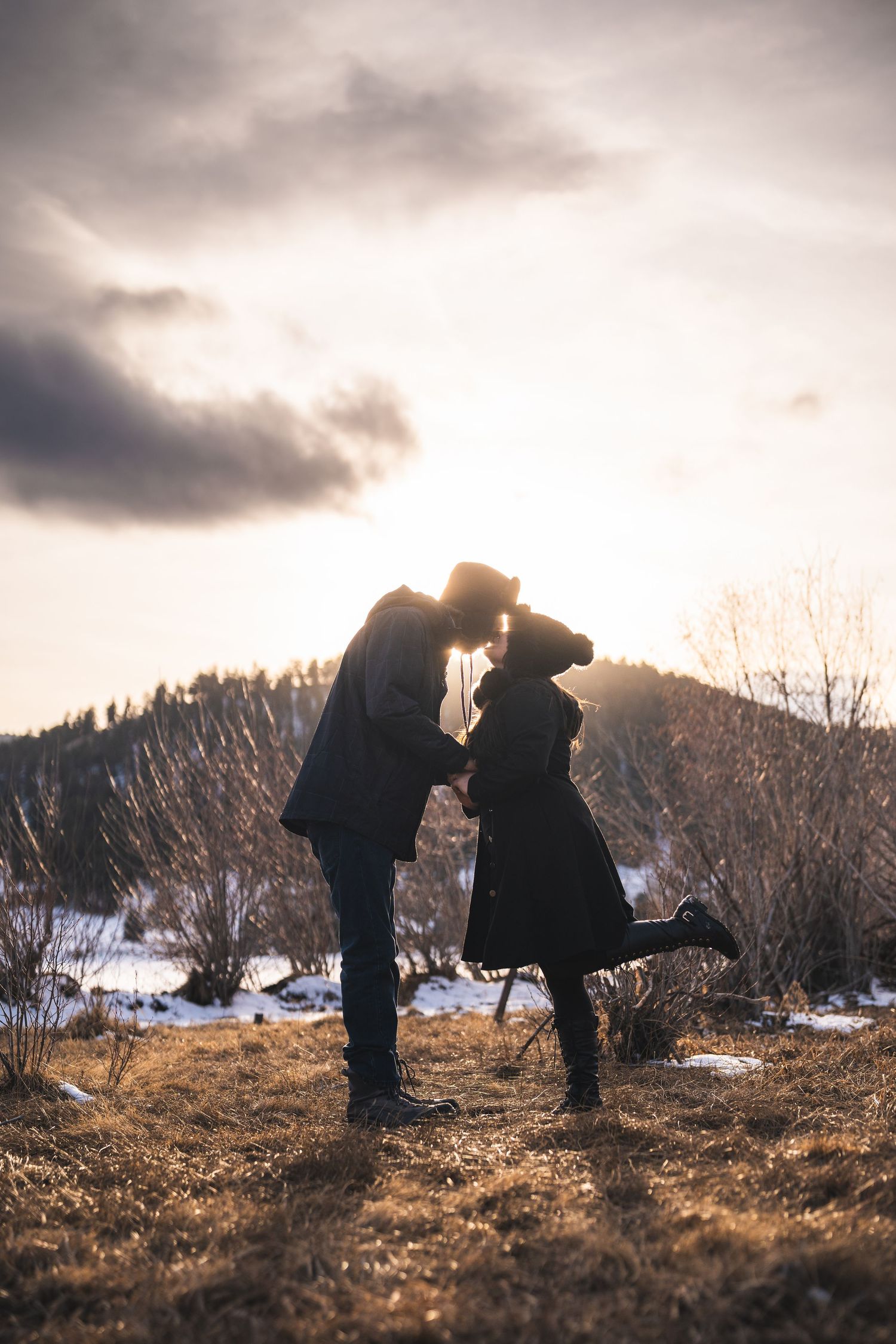 Silhouetted figures in winter landscape sharing intimate moments against snowy mountains.