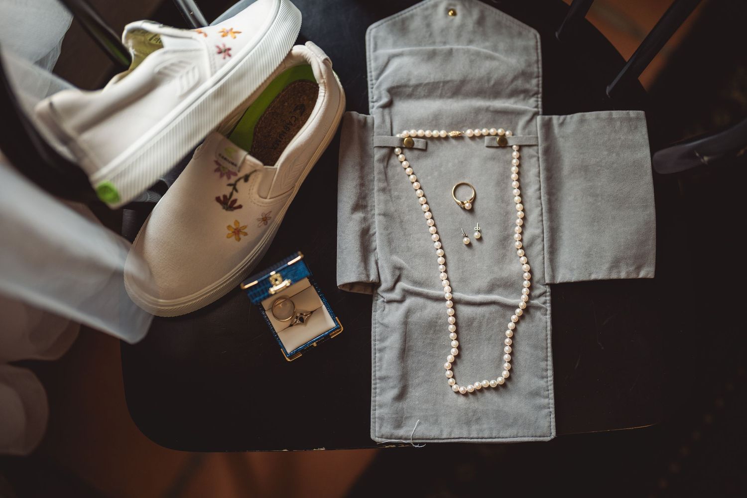 Jewelry and accessories laid out on a gray surface for wedding preparation.