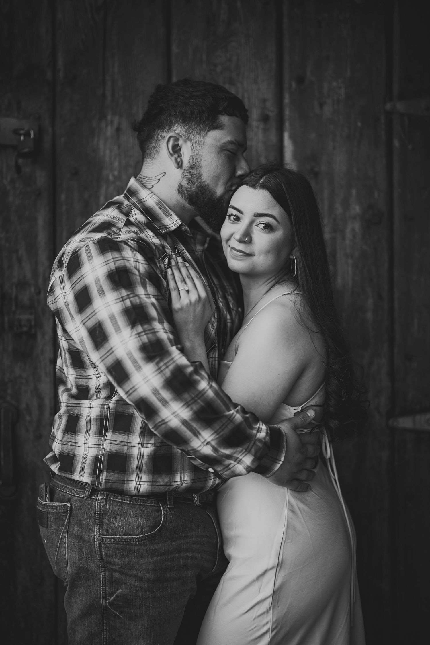 Intimate black and white portraits against rustic wooden barn wall background.