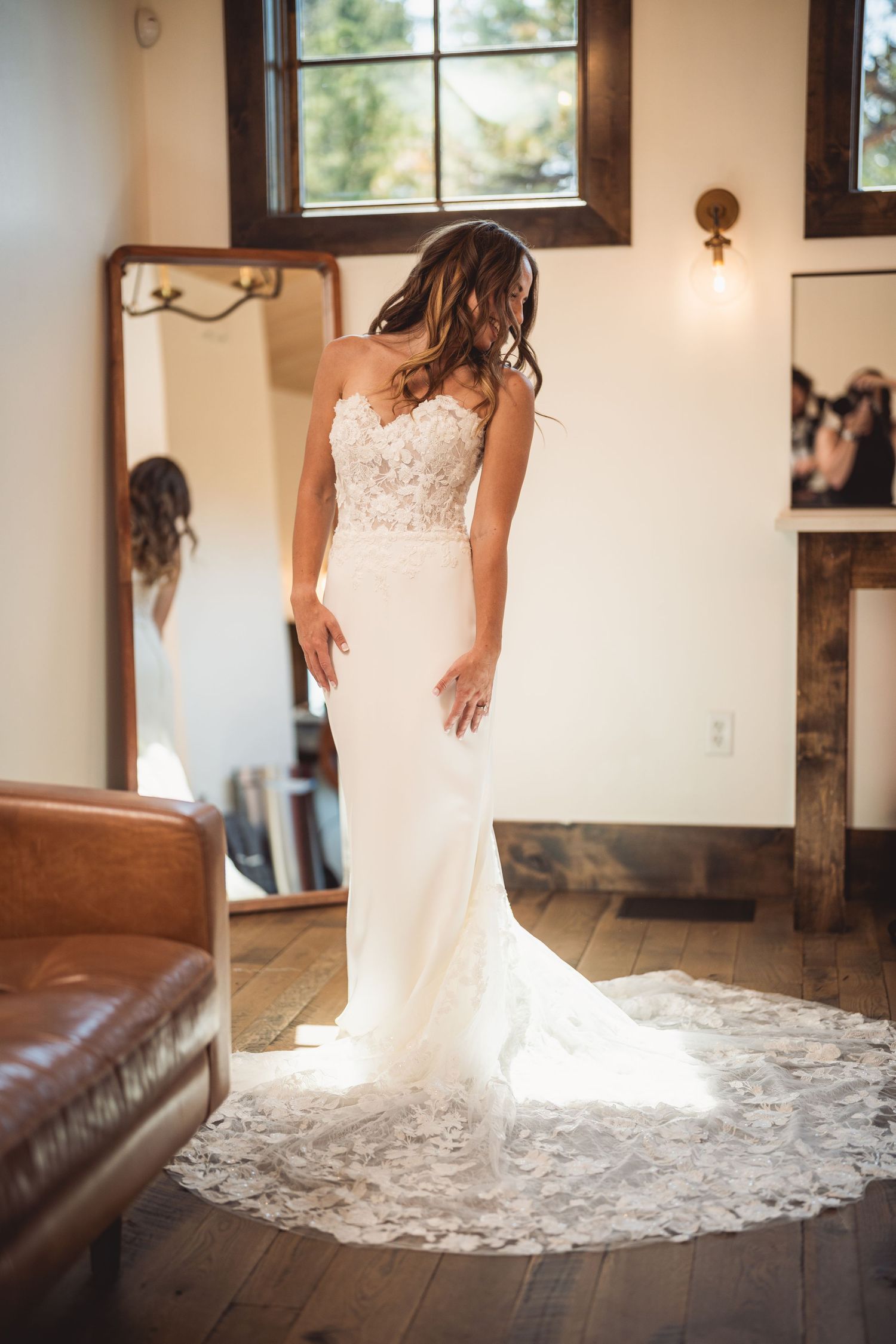 Beautiful lace train of wedding dress spreads across wooden floor.