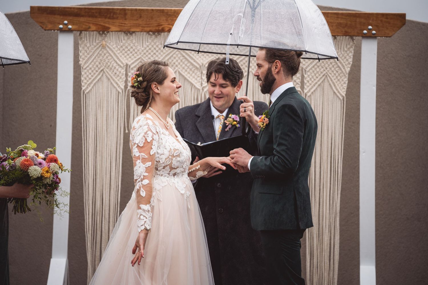 Couple sharing a romantic moment under white umbrellas at an indoor wedding venue.