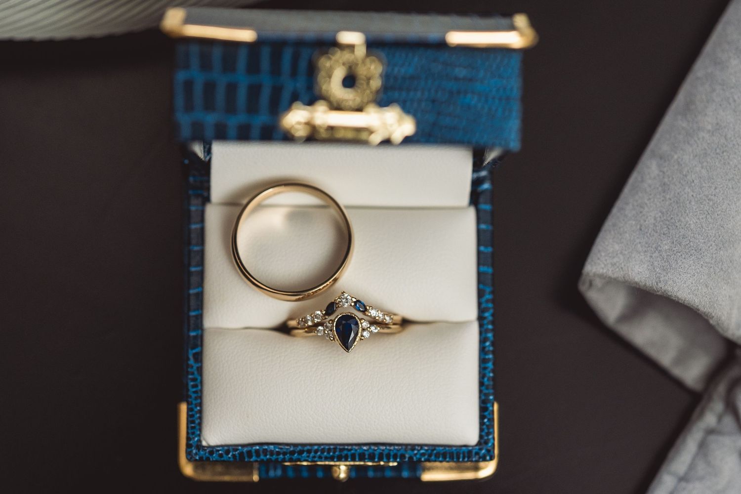 Wedding rings displayed in elegant blue jewelry boxes on dark background.