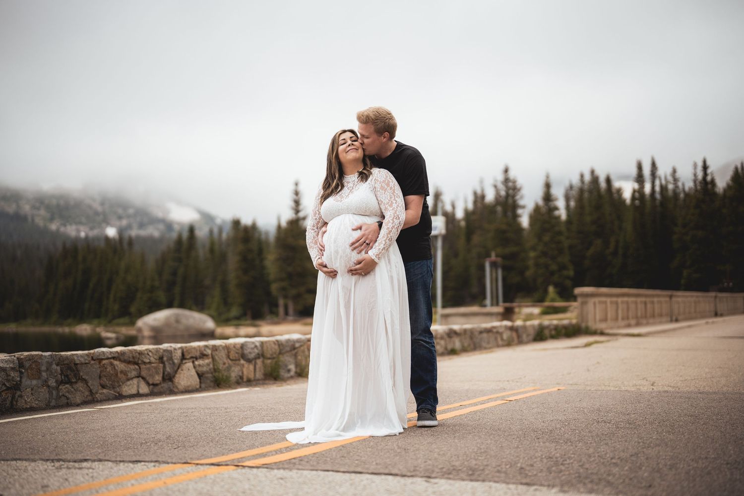 Romantic mountain top photo session with forest and cloudy sky background.