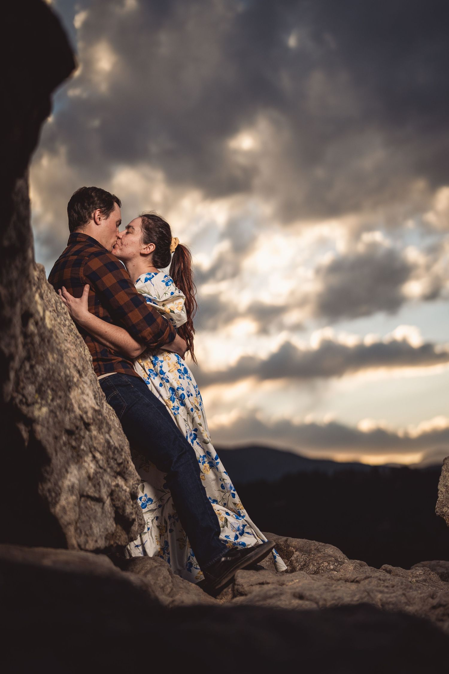Intimate moment captured on mountain rocks with stormy sunset sky.