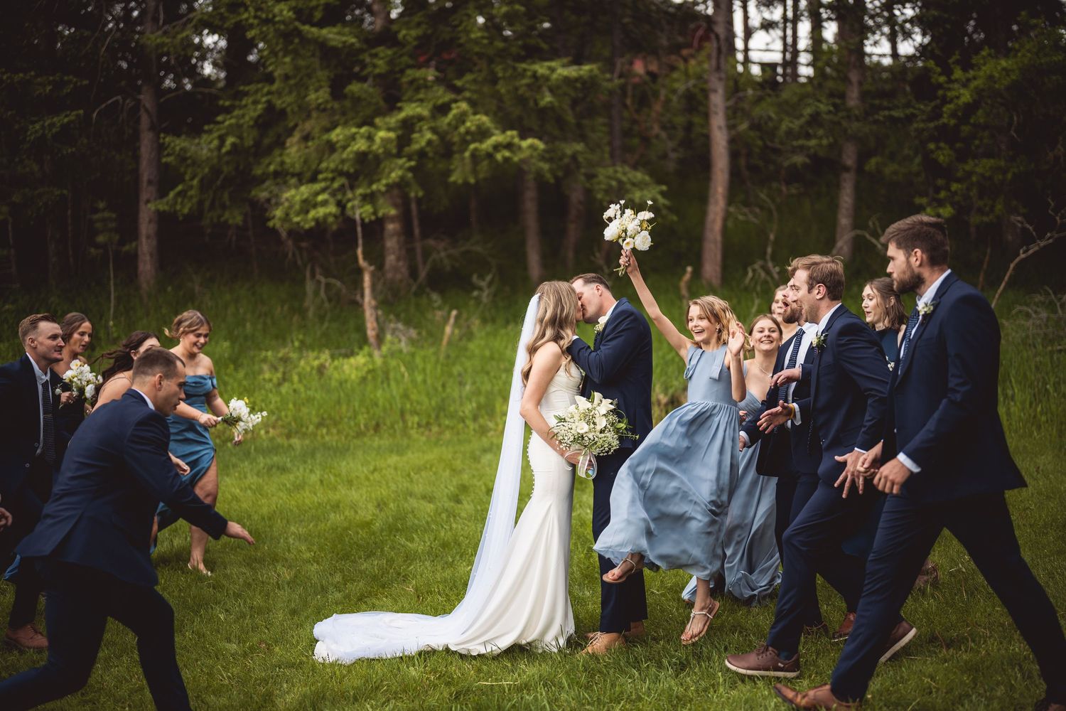 Wedding party poses in natural woodland setting with elegant attire.