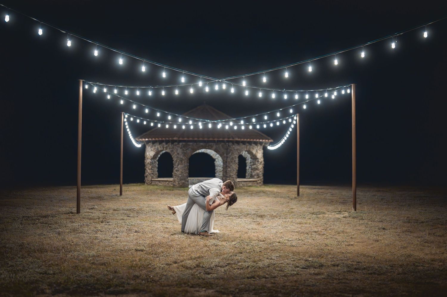 Wedding photos taken under romantic string lights at night in a rustic outdoor setting.