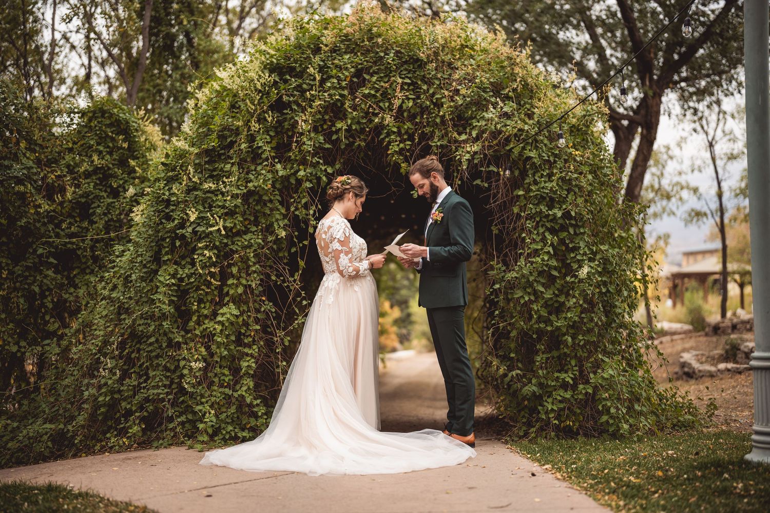 Wedding ceremony under lush green garden arch outdoors.