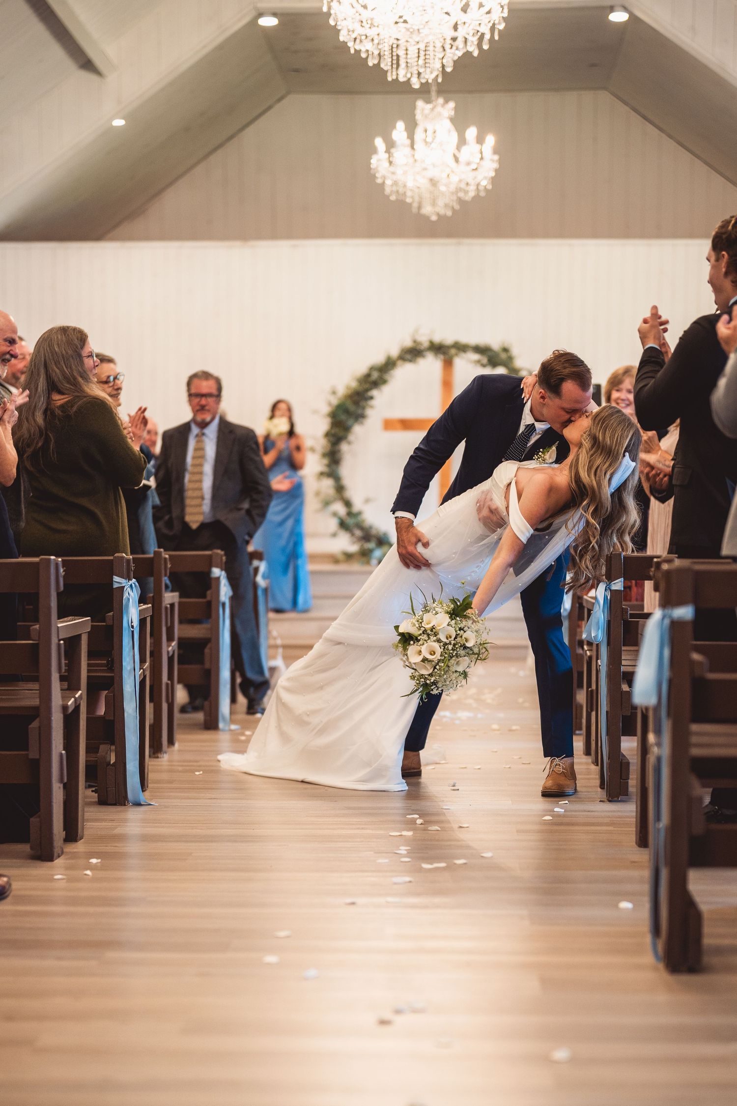 Wedding celebration moment in chapel aisle with crystal chandeliers overhead.