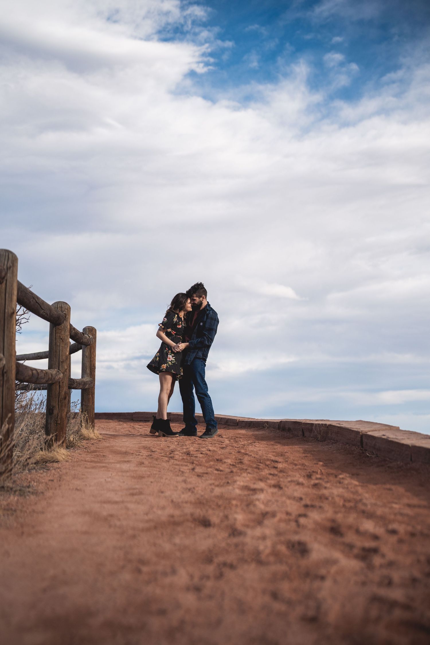 Two people sharing a tender moment on a red desert cliff overlook.