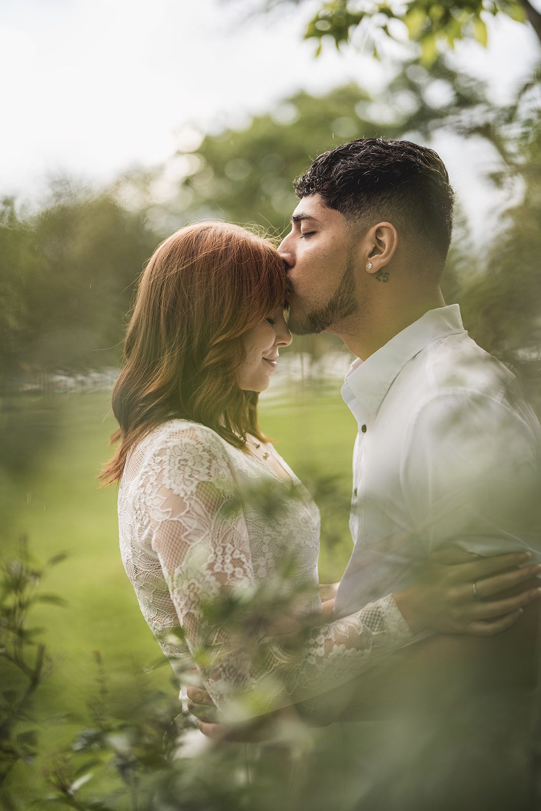 Romantic couple embracing in a lush green garden setting with soft focus.