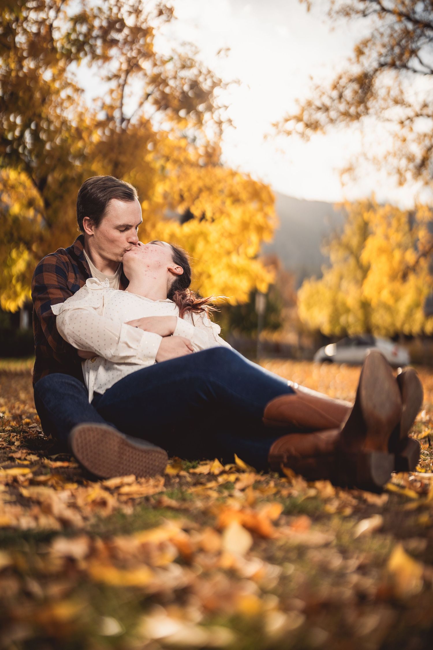 Intimate couple portrait among fallen autumn leaves at golden hour.
