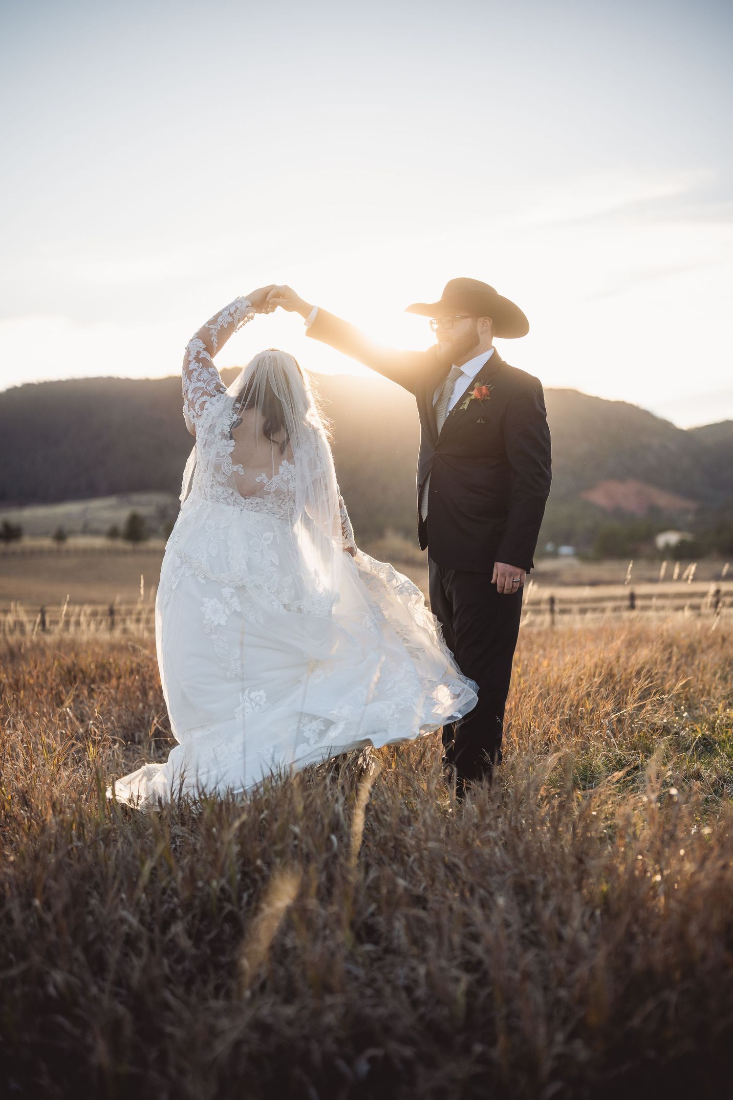 A golden hour portrait session with newlyweds walking through a rustic field.