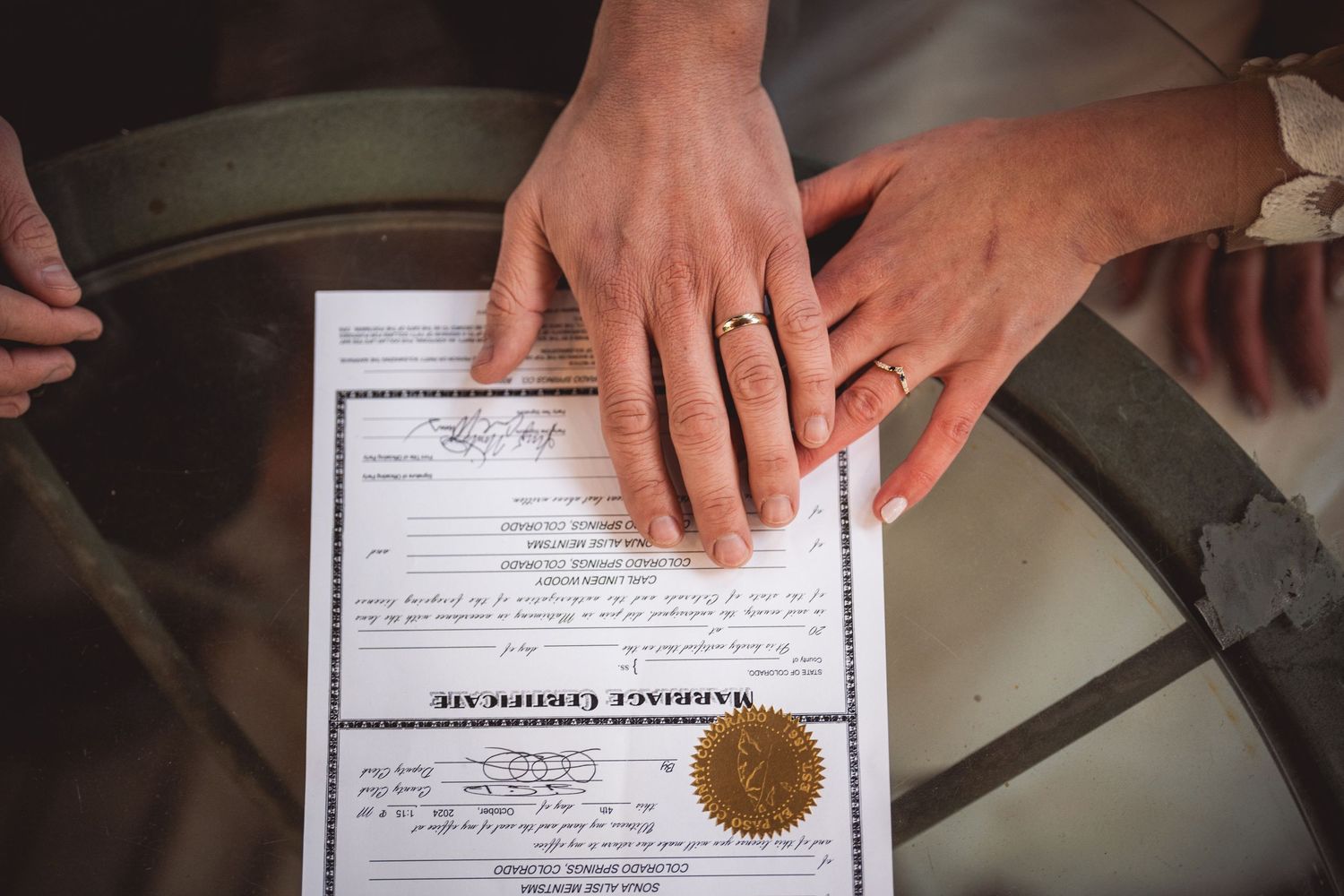 Close-up of hands placed on a marriage certificate with an official gold seal.
