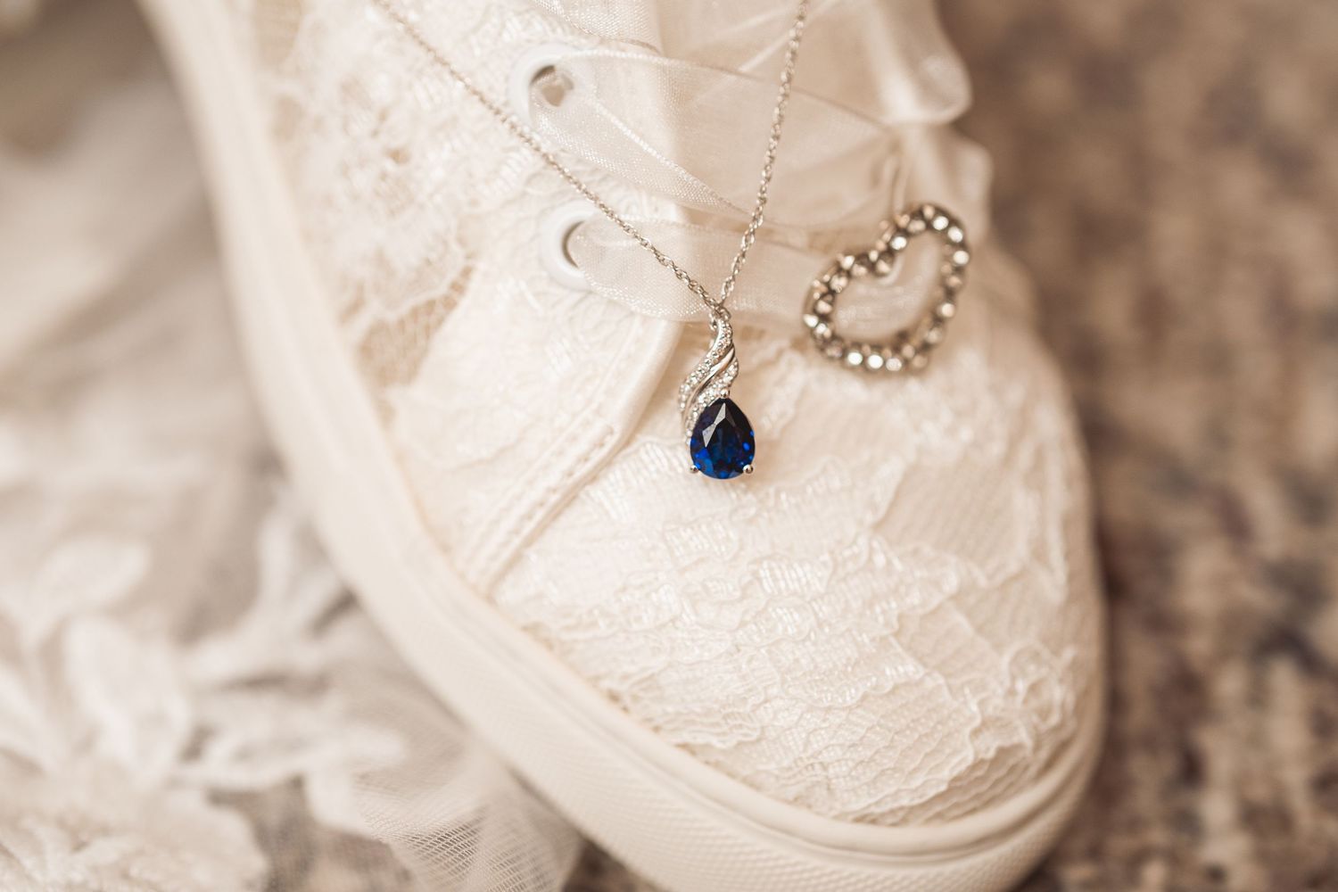 Close-up of wedding accessories including delicate jewelry on white lace.
