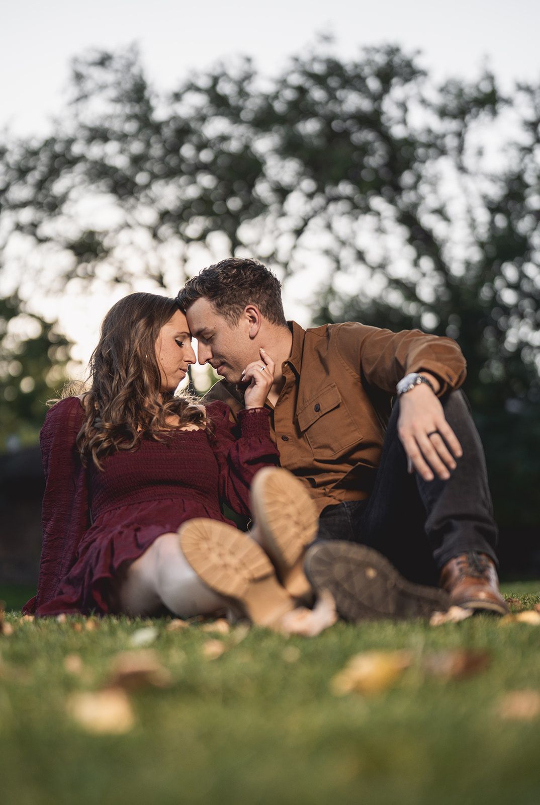 Couple lying on grass together sharing intimate moment during outdoor photo session.