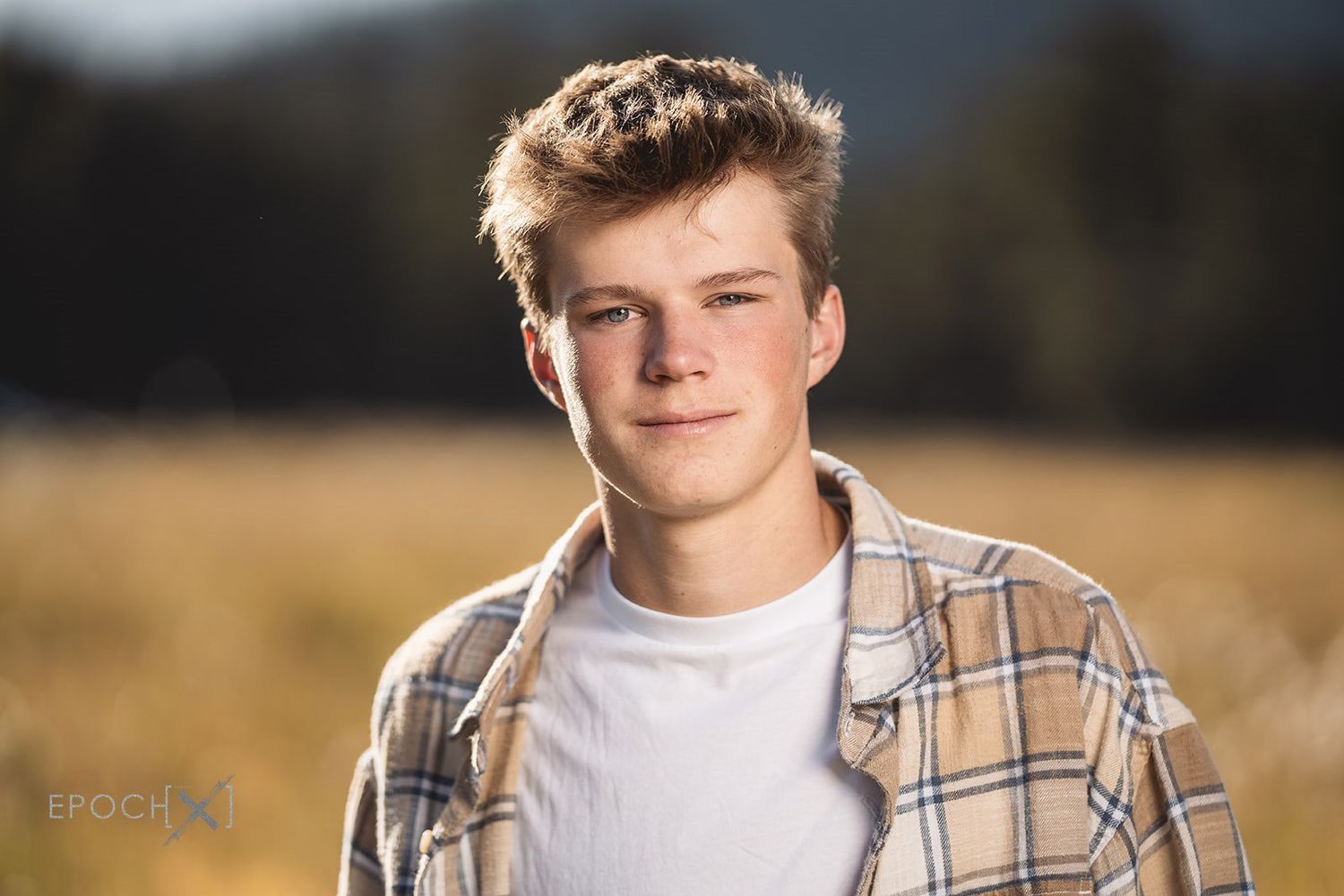 Portrait of a male student outdoors wearing plaid shirt.