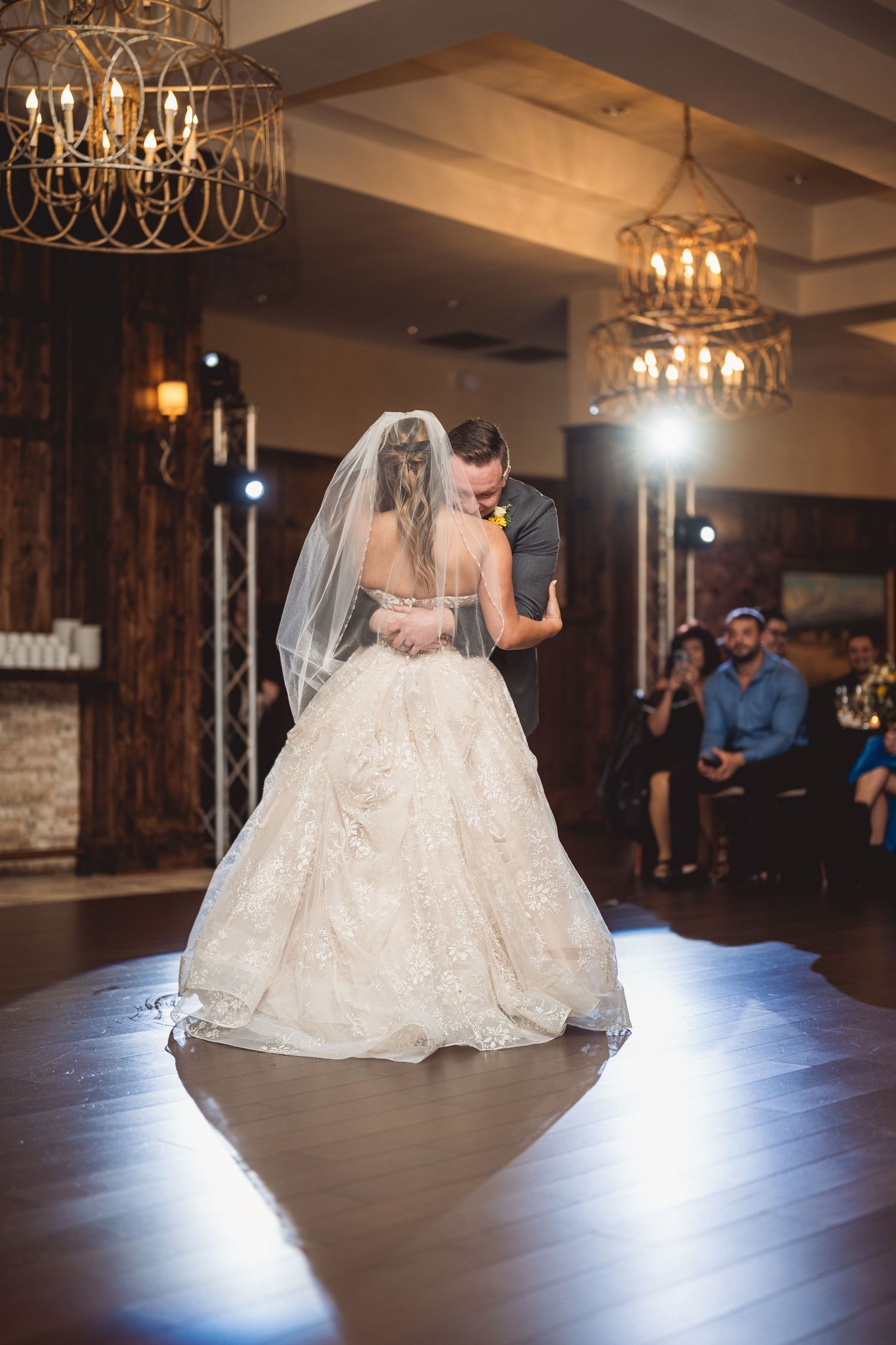 Couple performs romantic dance moves under elegant chandeliers during their wedding reception.