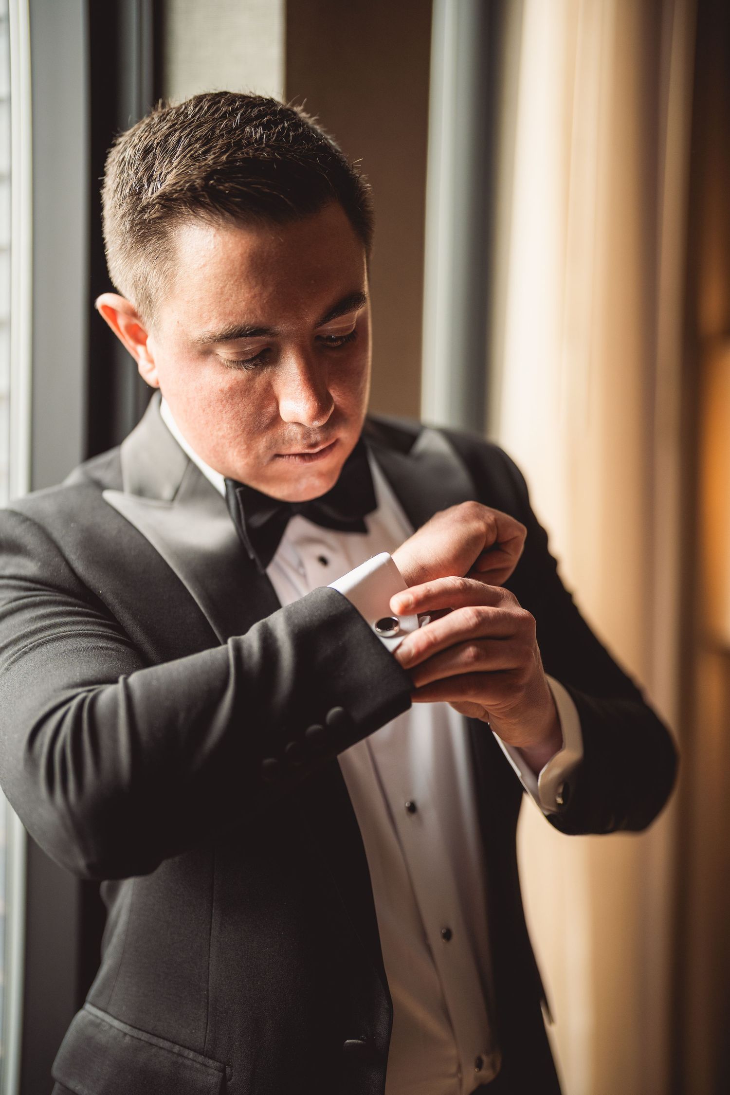 Person in tuxedo adjusting cufflinks while getting dressed.
