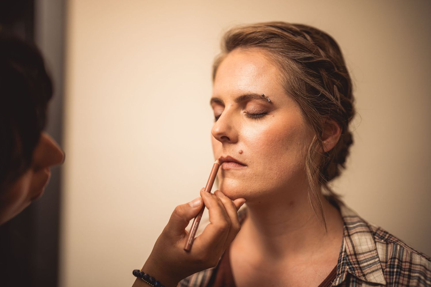 Close up shots of makeup being applied to a woman's face in warm lighting.