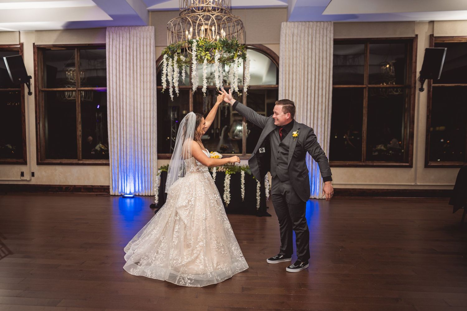 Elegant ballroom with blue uplighting and classical columns set for a wedding celebration.