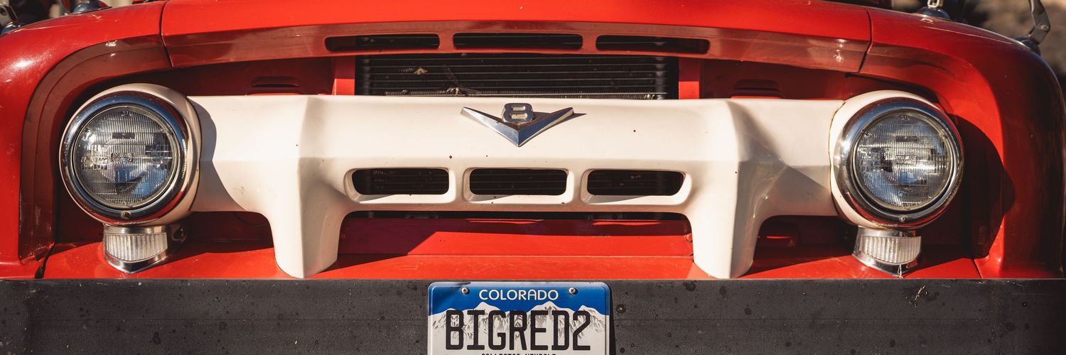 Classic red pickup truck front grille and headlights detail shot.