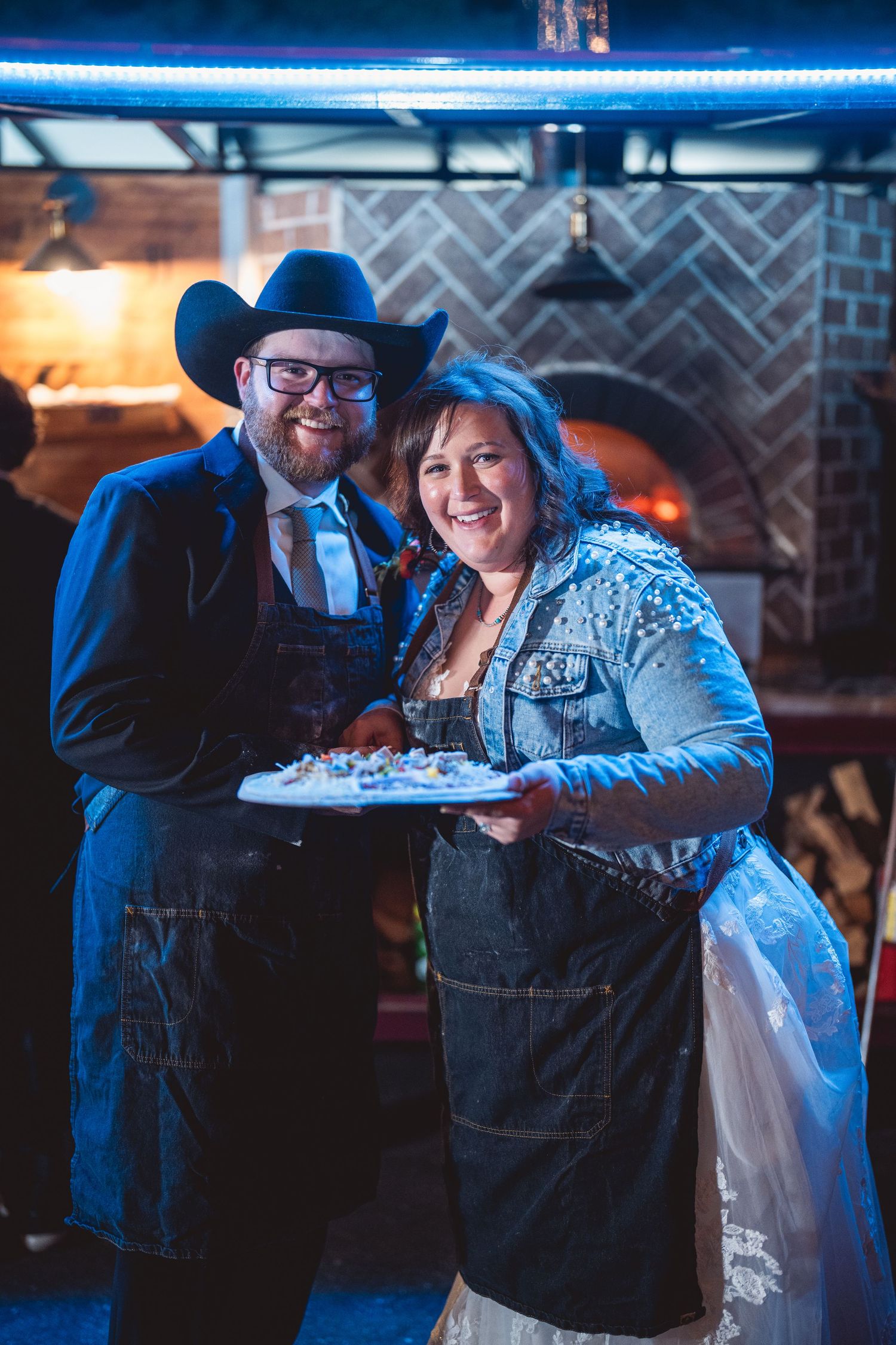 Couple sharing a fun moment at a western-themed wedding reception with blue lighting.
