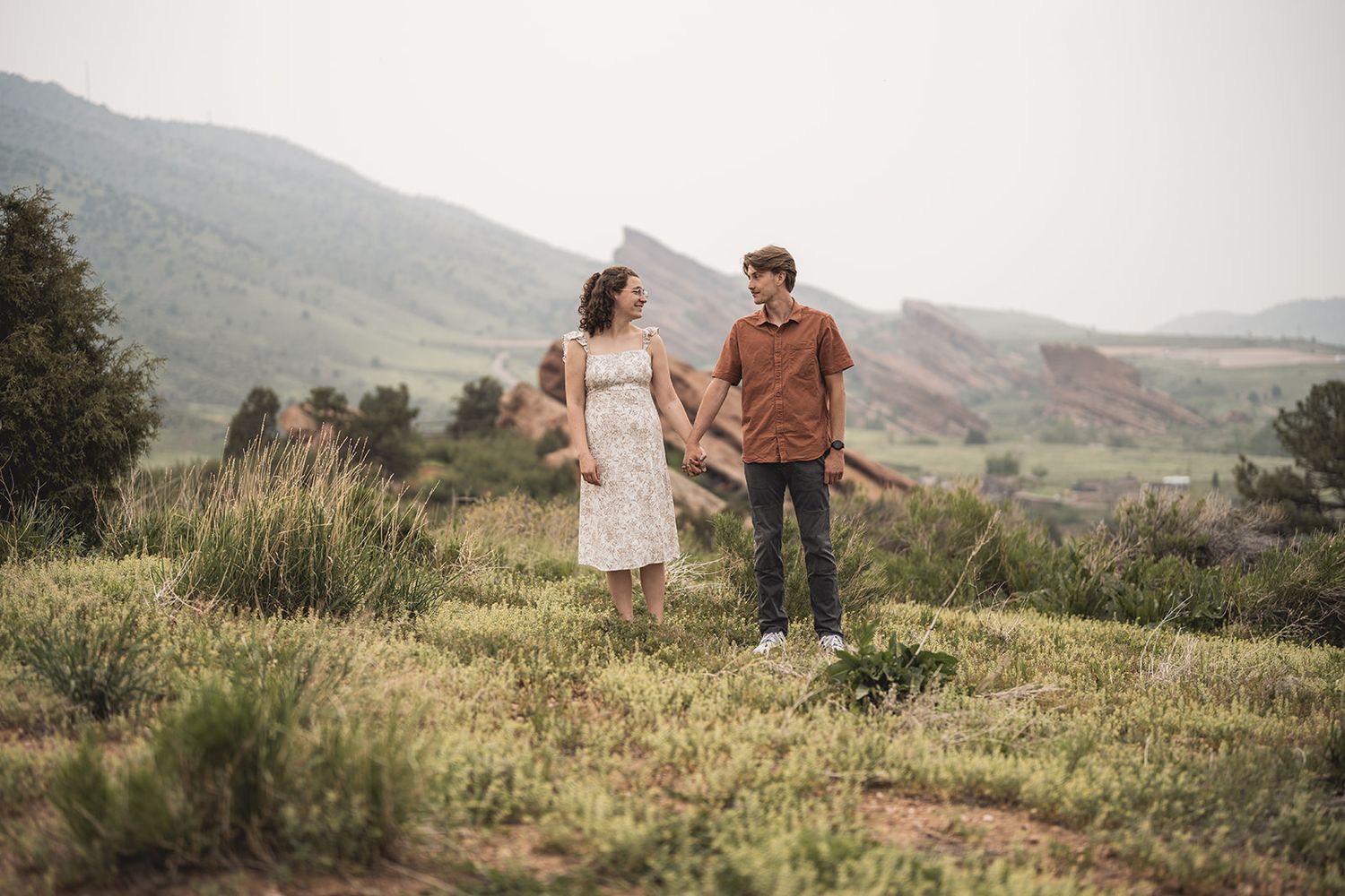 Couple enjoying a romantic stroll through scenic mountain terrain with dramatic landscape views.