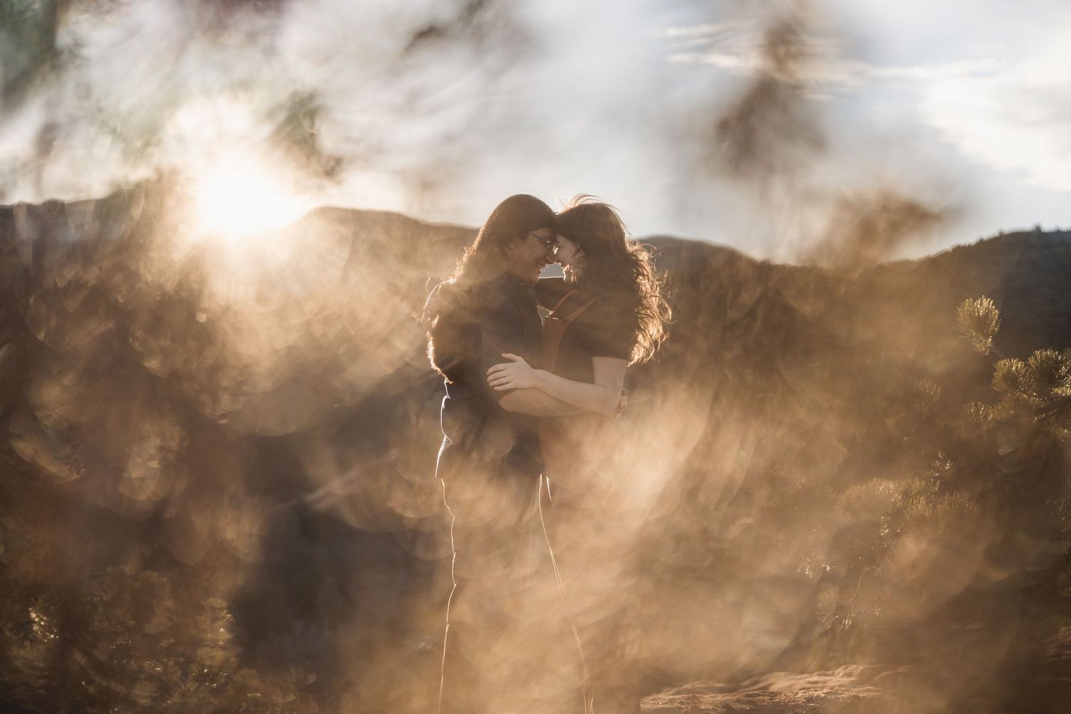 Sun rays break through misty mountain landscape creating ethereal golden atmosphere.