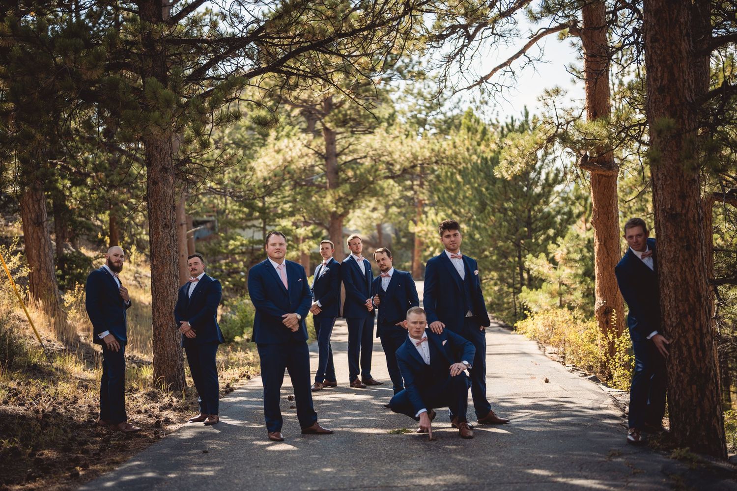 A wedding party arranged in front of tall pine trees at a mountain venue.