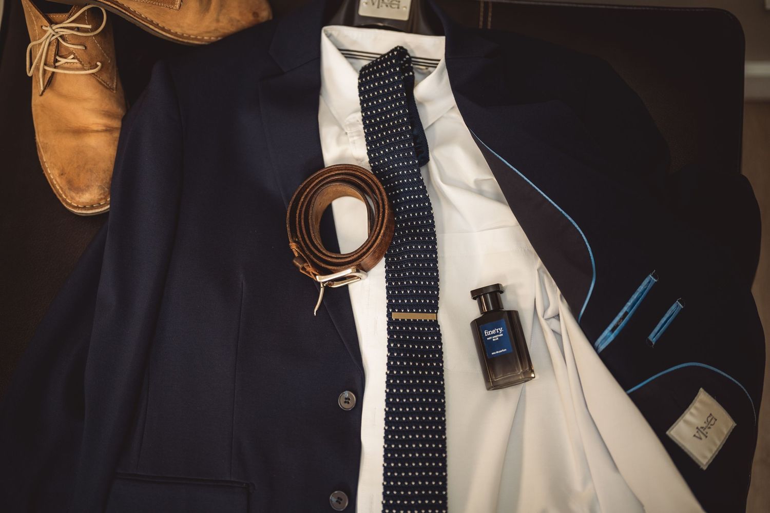 Detail shot of formal menswear including navy suit jacket and polka dot tie.