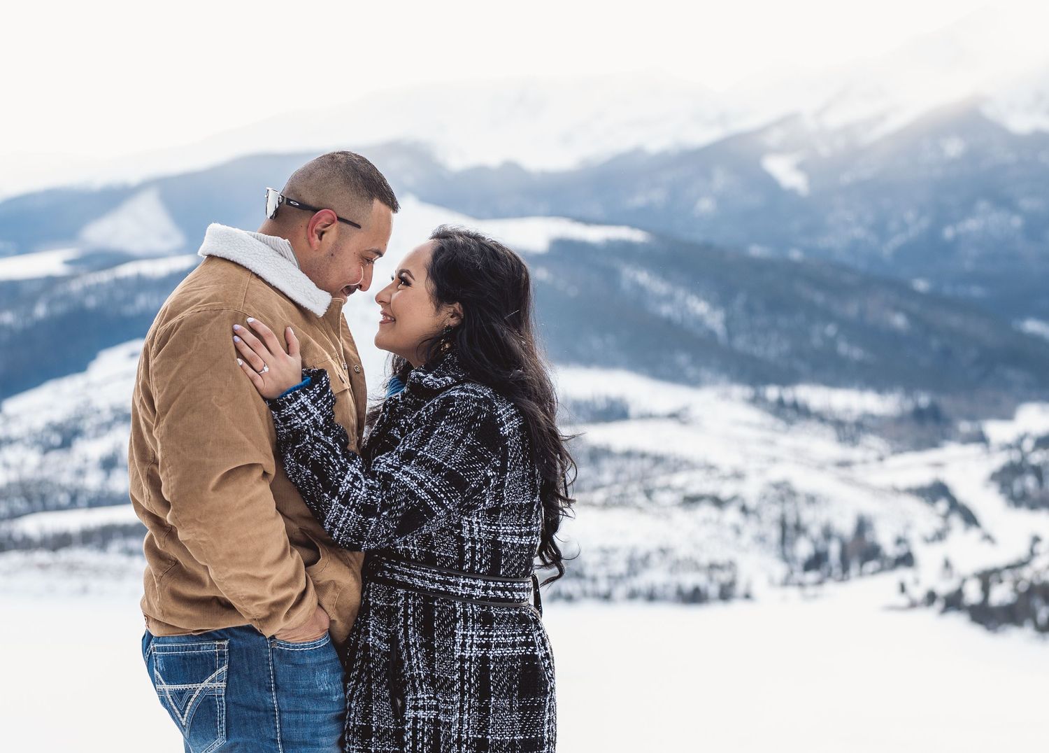 A winter engagement photo with snow-capped mountains creating a picturesque backdrop.