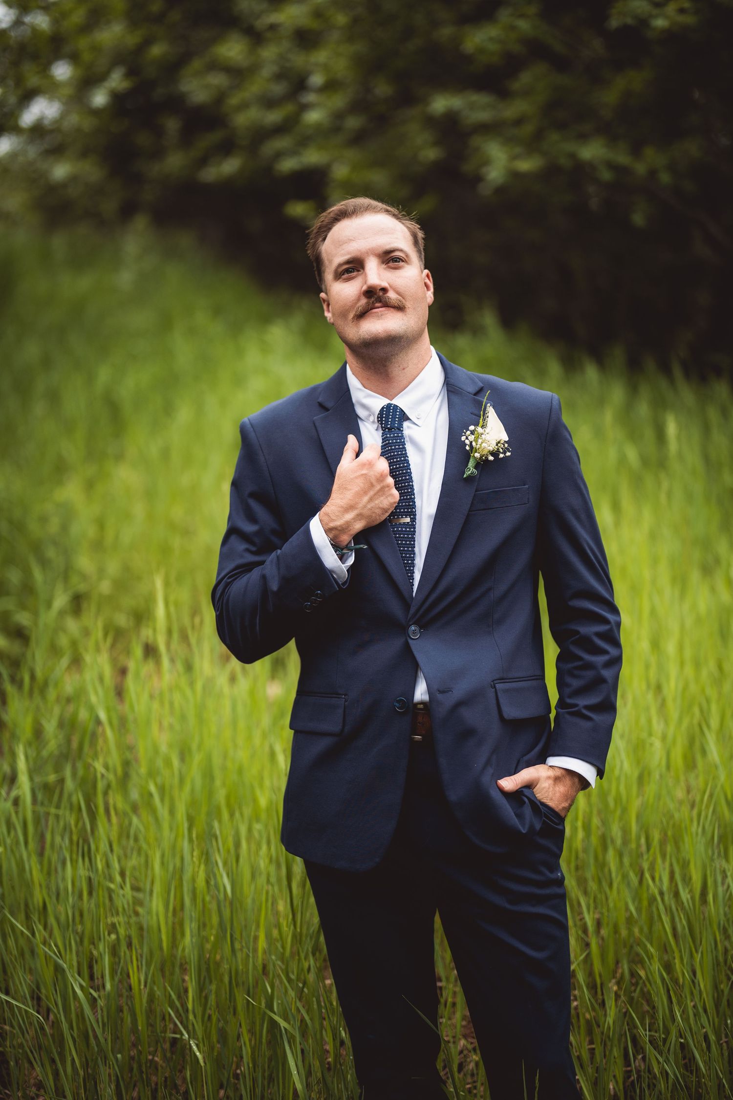 Candid shots of a groom in formal attire making expressive poses outdoors.