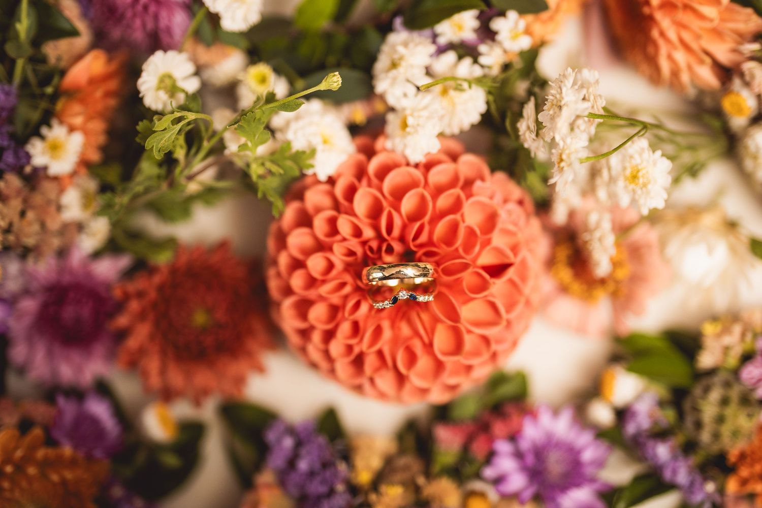 Colorful floral arrangement with orange dahlias, purple blooms and delicate white flowers.