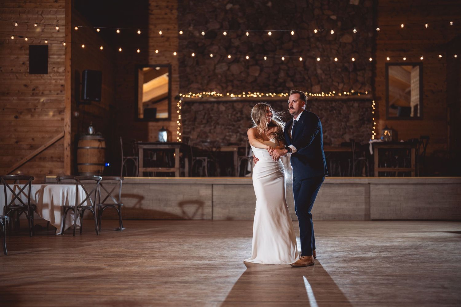 Romantic dance scene in rustic barn venue with warm lighting and exposed brick walls.
