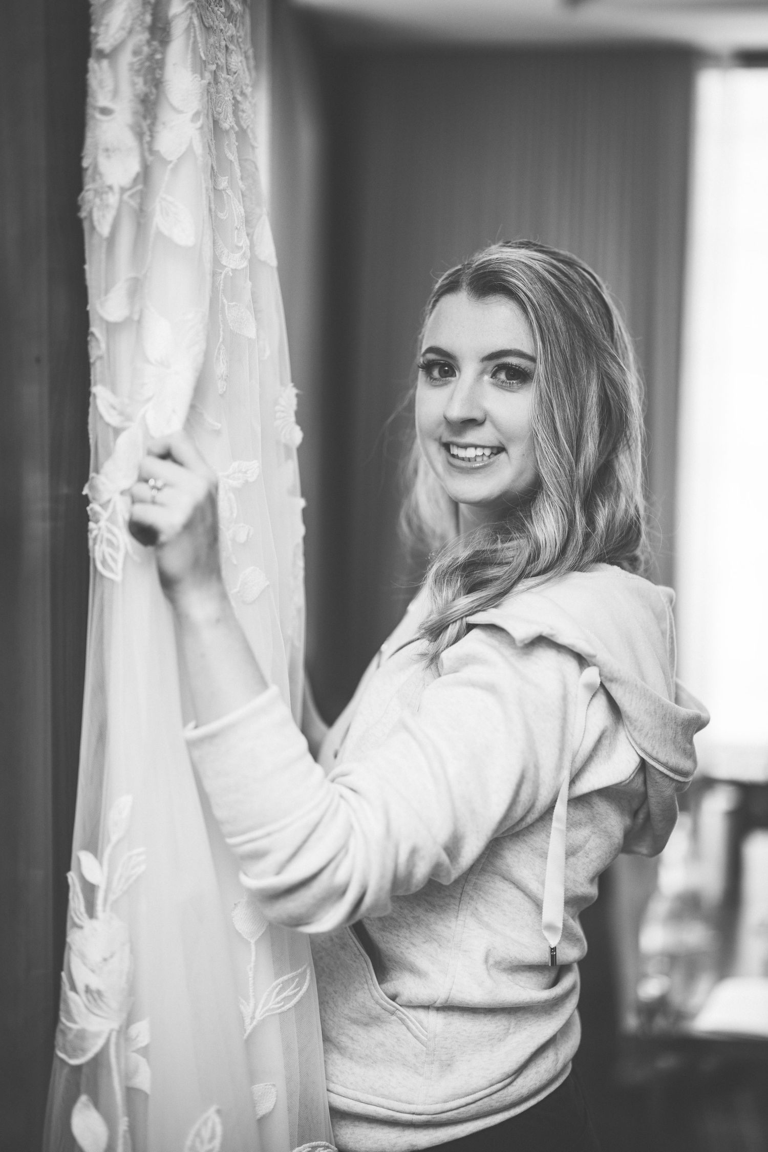 Black and white photo showing preparation moments with a wedding dress hanging.