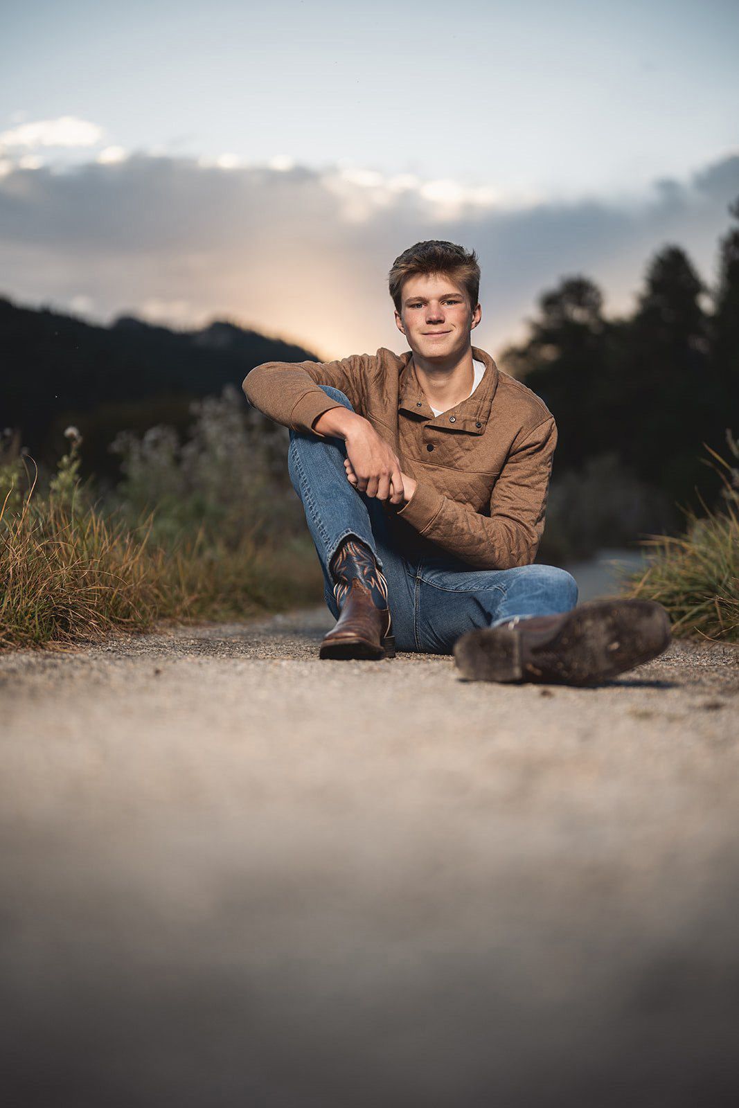 Casual outdoor portrait on ground with blurred foreground at sunset.