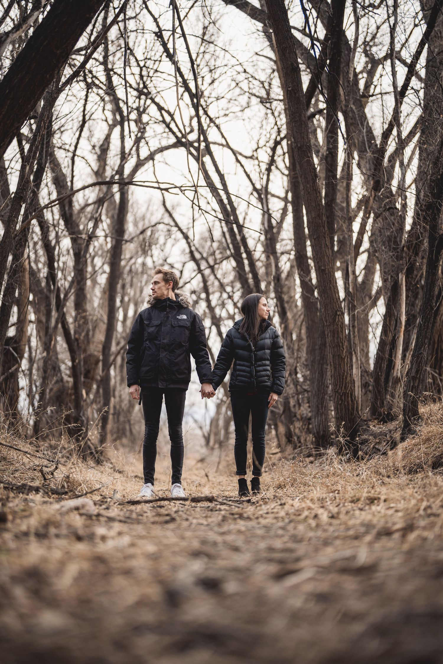 A couple walking through a wooded path in autumn.