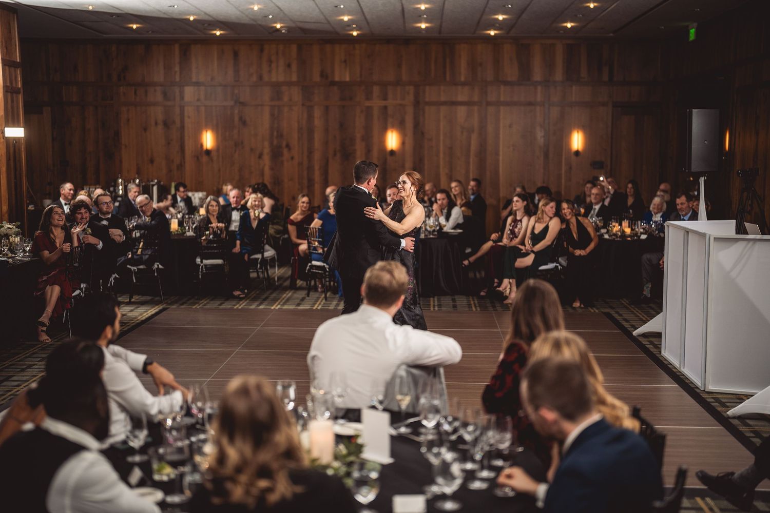 Panoramic view of an elegant indoor wedding reception with guests seated at tables.