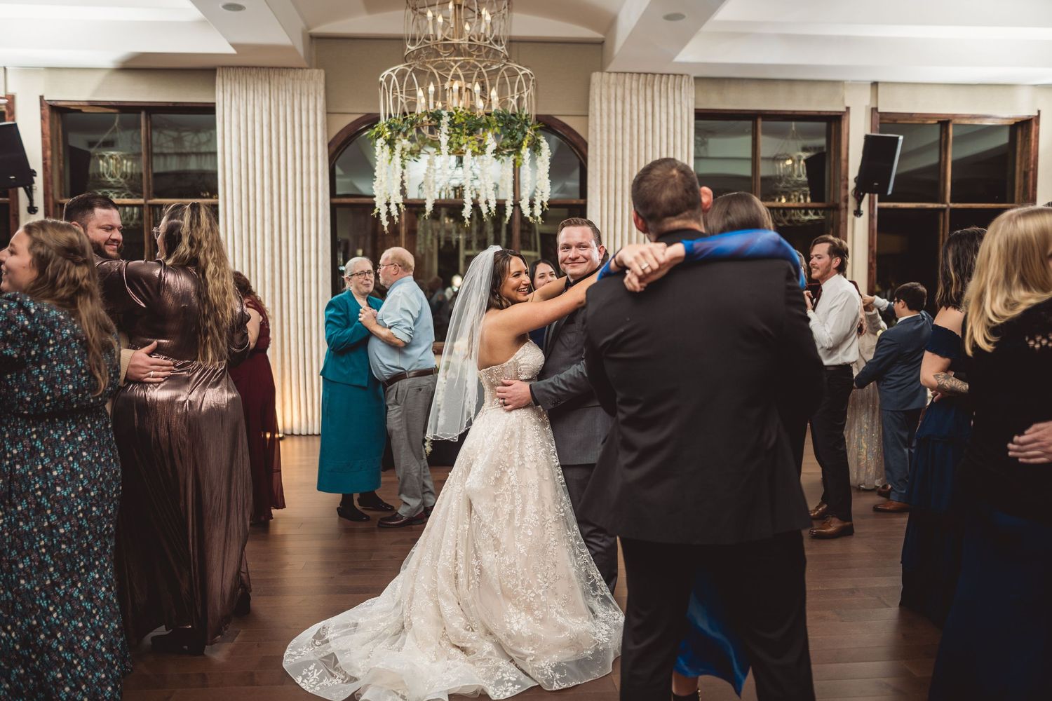 Wedding celebration in a grand ballroom with guests dancing and enjoying the festivities.