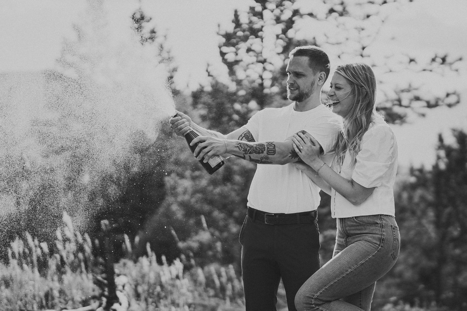 Joyful pair playing and dancing in a sunlit forest setting.